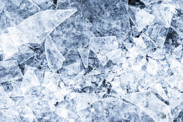 Thin ice fragments lay on a frozen lake surface, top view