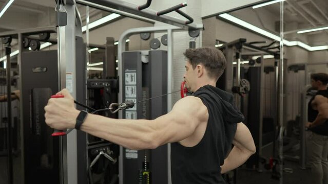 Mascular bodybuilder doing rear delt cable fly exercise in slow motion