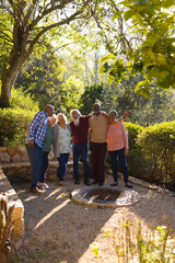 Happy diverse group of senior friends embracing and smiling in sunny garden