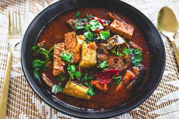 plant-based hot pot with tempeh and zucchini and mixed vegetables in spicy broth
