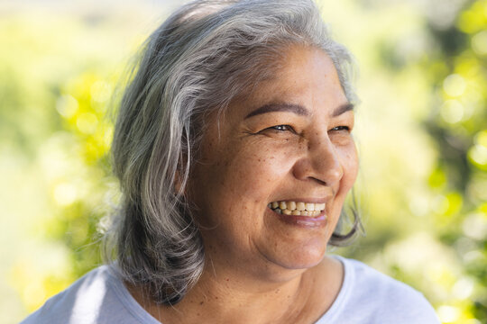 Portrait of happy biracial senior woman laughing in sunny garden, copy space