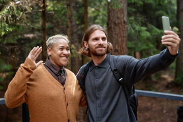 Young couple having video call on smartphone during their hiking in the forest