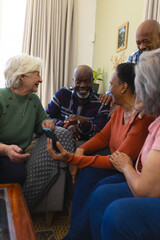 Happy diverse group of senior friends having video call and discussing in sunny living room