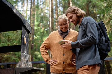 Obraz premium Young couple using smartphone together during their hiking in the forest