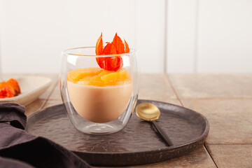 A glass of traditional Italian dessert panna cotta with peaches on the table