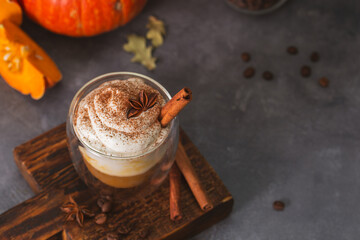 A glass of autumn pumpkin latte with whipped cream and spices. Coffee with pumpkin and cinnamon on a dark background, copy space