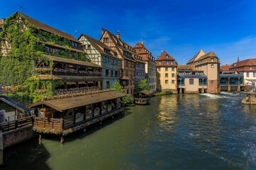 Fototapeta na wymiar Ornate traditional half timbered houses with blooming flowers along the canals in the picturesque Petite France district of Strasbourg, Alsace, France 