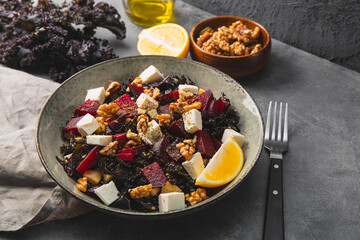 Obraz na płótnie Canvas Salad of kale, roasted beets, walnuts and feta cheese on the table close up