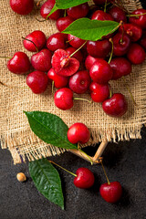 Sweet red cherry on burlap on a black background. A large number of cherries with leaves on the table, on a black background. close-up.