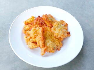 fried corn.  Perkedel jagung. Corn fritters on a plate on a gray background. Yummy Indonesian Sweetcorn Fritters. very popular in Indonesia. a snack that is often enjoyed as a snack or side dish. 