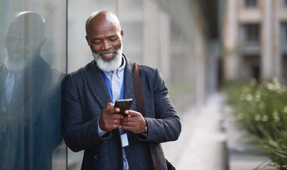 Phone, business and senior black man in city, texting or internet browsing outdoors in urban street. Technology, cellphone and happy male ceo with 5g mobile smartphone for networking or social media. - obrazy, fototapety, plakaty