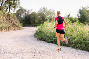 rear view of a woman running in the countryside, concept of sport in nature and active lifestyle, copy space for text