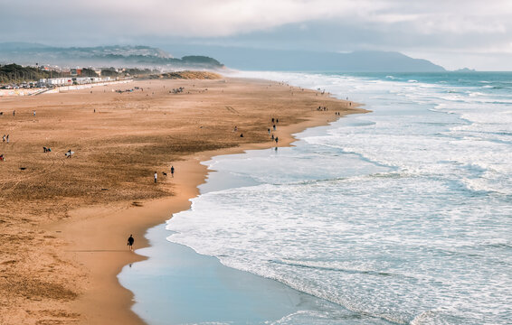 People walk along the beach at Ocean Beach, San Francisco. Pacific Ocean.