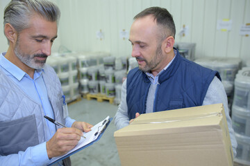 two couriers with a parcel signing a delivery form