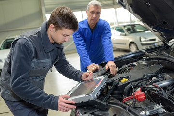 auto mechanic teacher and trainee performing tests at mechanic school