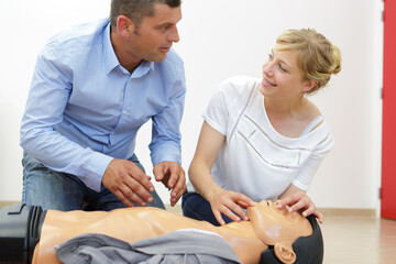 woman demonstrating cpr on training dummy in first aid class