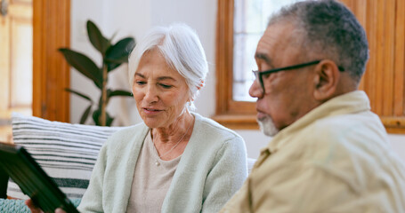 Tablet, love and a senior couple on a sofa in the living room of their home to search social media together. Interracial, app or tech with an elderly man and woman in the apartment for retirement
