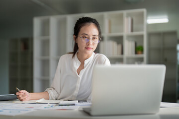 Portrait of beautiful young businesswoman asian sitting at office modern work station and typing on laptop - obrazy, fototapety, plakaty