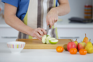 man cuts apple on wooden table