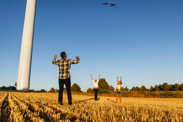 Family of three playing with a kite outdoors.