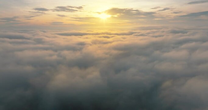 Aerial4K drone in sky is raising above from the thick fog above the beautiful ocean of clouds at sunrise. Sun is rising above the endless sea of clouds until the horizon. Amazing nature landscape