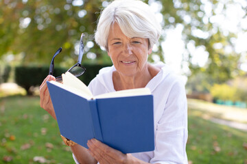 retired woman reading a book at the park