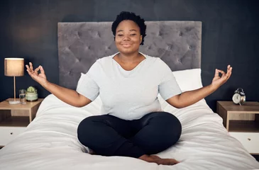 Fototapeten Yoga, lotus and portrait of black woman on bed for meditation, mindfulness or exercise. Pilates, workout or person in bedroom for zen, relax and plus size body for health, wellness or fitness at home © David Lahoud/peopleimages.com