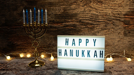 Hand put Candlestick near Happy Hanukkah signboard 