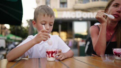 Mom son eating ice-cream in street cafe sitting at table talking spending time together on weekend. Family resting smiling blonde woman pre-teen boy in city. Parenting, enjoying motherhood concept.