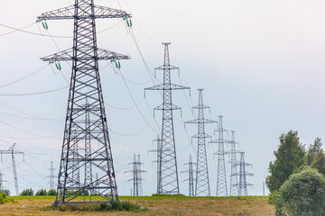 Metal electric poles against a gray sky with clouds