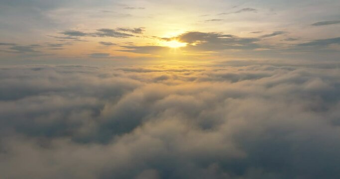 Aerial4K drone in sky is raising above from the thick fog above the beautiful ocean of clouds at sunrise. Sun is rising above the endless sea of clouds until the horizon. Amazing nature landscape