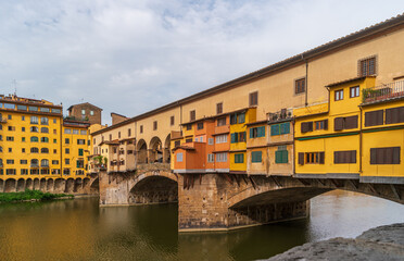 Fototapeta na wymiar Florence, Italy. Bright colors of the Ponte Vecchio bridge over the Arno river on a summer day. Famous tourist attraction in the Italian region of Tuscany.