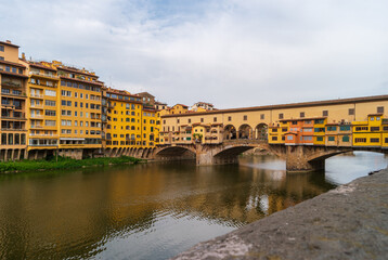 Fototapeta premium Florence, Italy. View of the Ponte Vecchio bridge over the Arno river on a summer day. Famous tourist attraction in the Italian region of Tuscany.