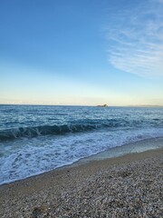 spiaggia al tramonto con sassi e isoletta nel mediterraneo