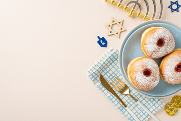 Prepare Hanukkah-themed table arrangement. Top-view image featuring customary Jewish delicacies – sufganiyot, napkin, cutlery, Star of David, menorah, gelt on neutral beige surface with space for text