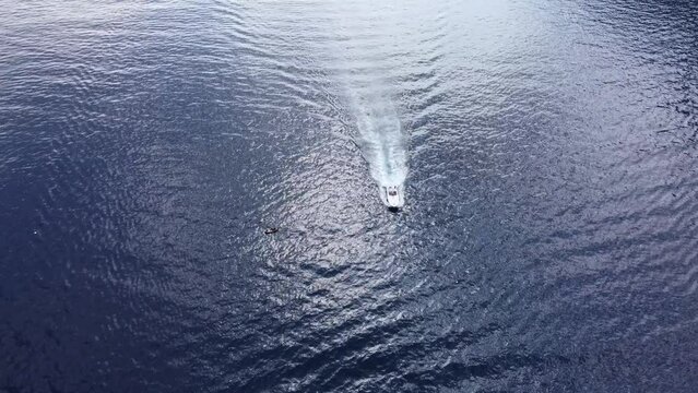 Drone shot of luxury motorboat in ocean waters near marina. Panning shot of yacht swim and raise waves in open blue waters. Amazing epic background over waves in sea