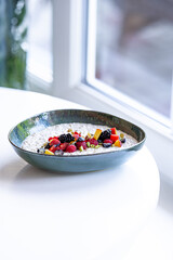 semolina porridge with berries in a plate on the white table