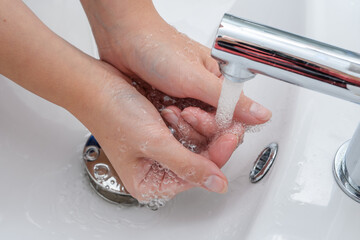 Kobieta myje dłonie w umywalce w łazience  - obrazy, fototapety, plakaty