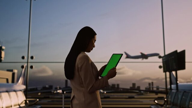 Asian Businesswoman Using Green Screen Tablet In Boarding Lounge At The Airport
