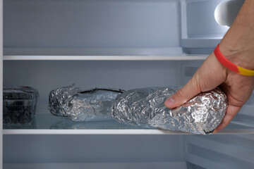 Domowa kanapka zawinięta w folię aluminiową odkładana na półkę w lodówce  - obrazy, fototapety, plakaty