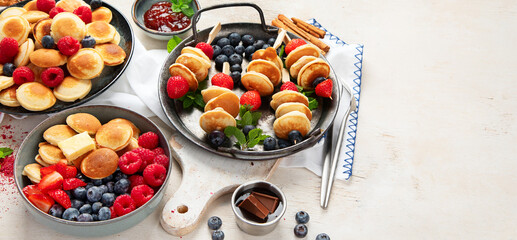 Delicious pancakes with blueberry, strawberry and raspberry. Sweet and tasty breakfast on ligt background