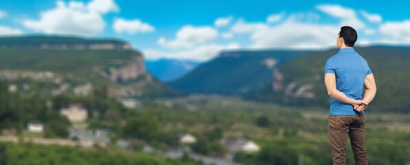 Naklejka premium Person stands on a mountain peak looking in beautiful view