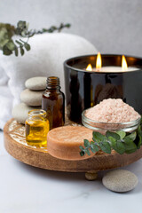 Obraz na płótnie Canvas Spa set on a wooden stand, eucalyptus branches, aroma oils, candles and stones. Spa treatments, massage, relaxation and beauty concept.