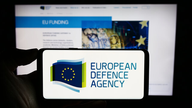 Stuttgart, Germany - 10-17-2023: Person holding mobile phone with logo of EU institution European Defence Agency (EDA) in front of web page. Focus on phone display.
