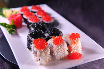Sushi on a white plate with red and black caviar dark background delicious food