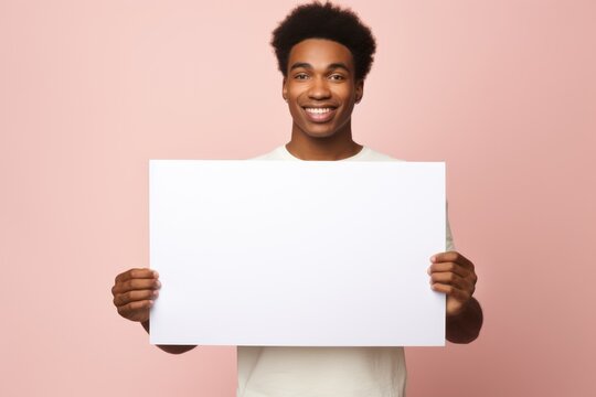 a handsome smiling african man holding a blank placard sign poster paper in his hands
