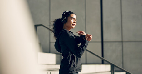 Runner girl, headphones and stretching arms on stairs for music, vision and ideas in city, workout and training. Woman, thinking and listen on steps with streaming subscription, wellness and warm up
