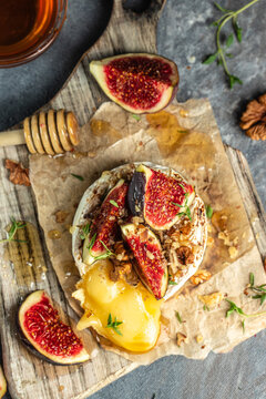 Baked camembert with nuts and honey, fig and thyme, vertical image. top view. place for text