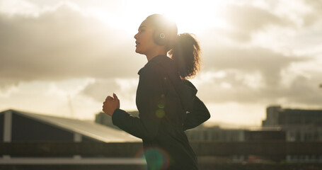 Woman, morning and running in city with headphones for fitness, workout and marathon training...