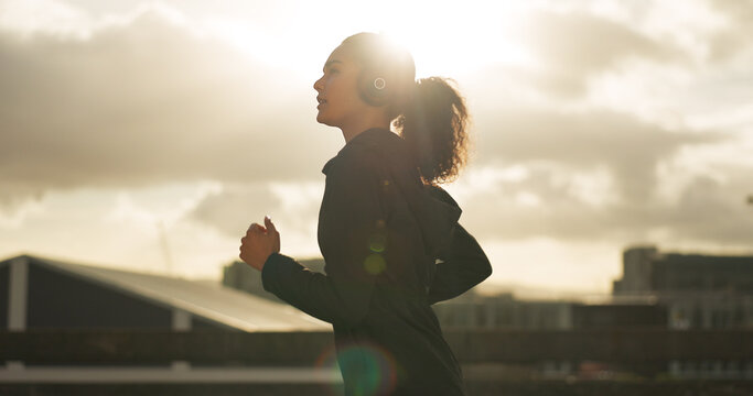 Woman, morning and running in city with headphones for fitness, workout and marathon training music. Sun lens flare, athlete or exercise podcast in Brazil for cardio wellness, health or sports radio